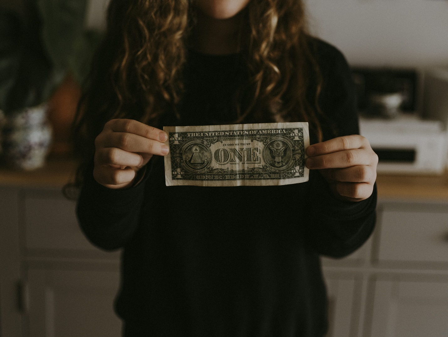 A one-dollar bill held by a woman
